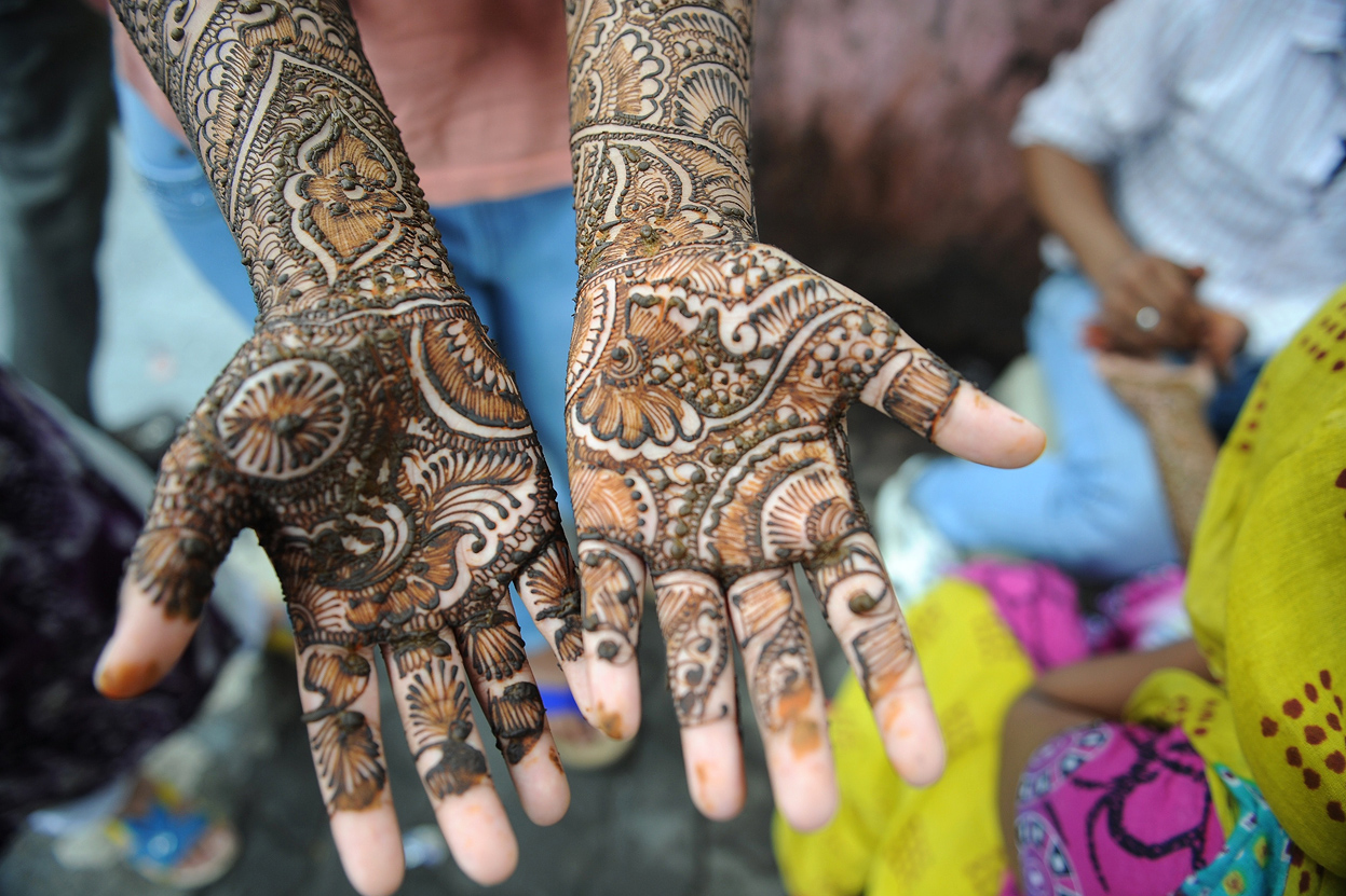 An Indian Muslim girl waits for her henna-decorated hands to dry at a roadside stall ahead of the Muslim festivities of Eid al-Fitr, in Mumbai