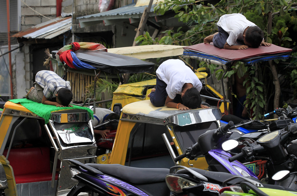 Muslim youths pray atop motorcycle taxis during the fasting month of Ramadan in front of Al-Satie Mosque in Baseco, Tondo city, metro Manila,