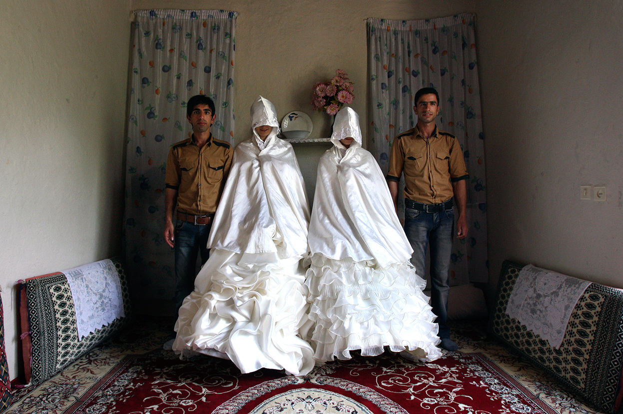  Iranian grooms, Javad Jafari, left, and his brother, Mehdi, right, pose for photographs with their brides, Maryam Sadeghi, second left, and Zahra Abolghasemi, who wear their formal wedding dresses prior to their wedding in Ghalehsar village, about 220 mi (360 km) northeast of the capital Tehran, Iran, on July 15, 2011. (AP Photo/Vahid Salemi)