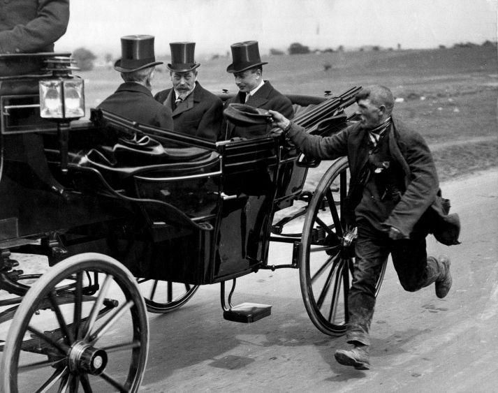 A beggar running alongside king Goarge V coach 1920