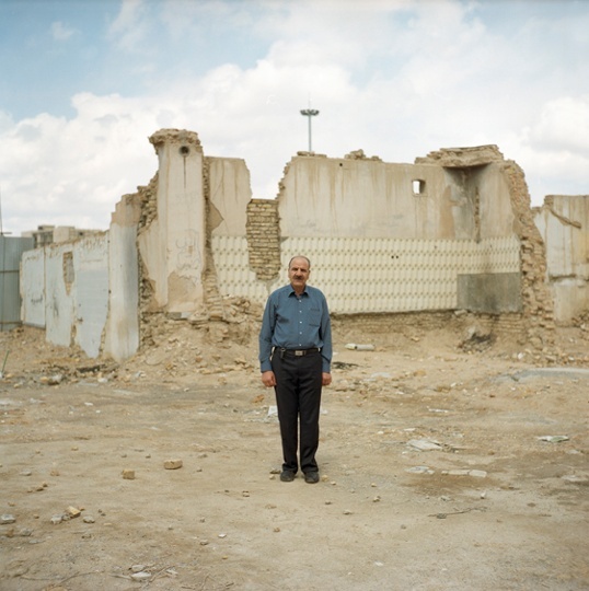 A man stands against a backdrop of ruins in Yazd.